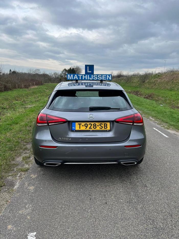 Het blauwe daklichtbord met de naam Mathijssen op de lesauto